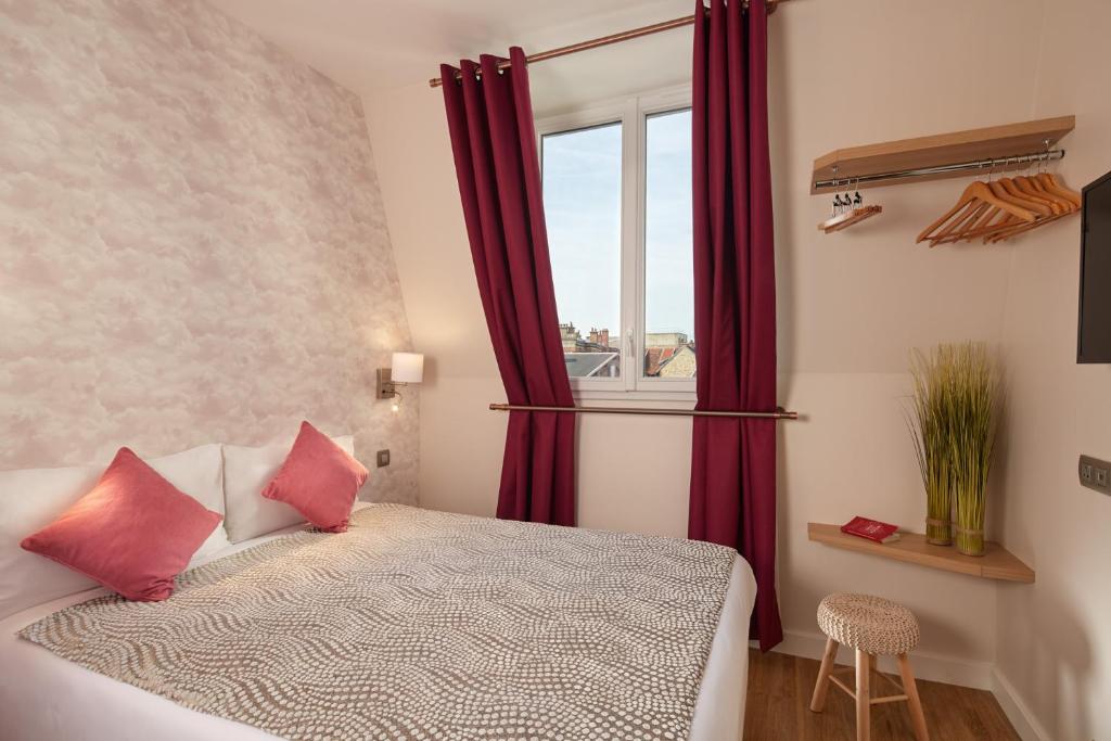 a bedroom with a bed with red curtains and a window at Hôtel Villa Sorel - Paris Boulogne in Boulogne-Billancourt