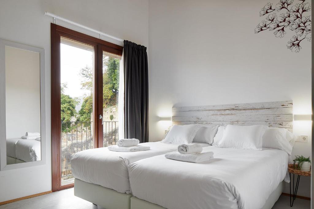 a white bedroom with a large white bed and a window at IRAIPE Estella Rooms in Estella