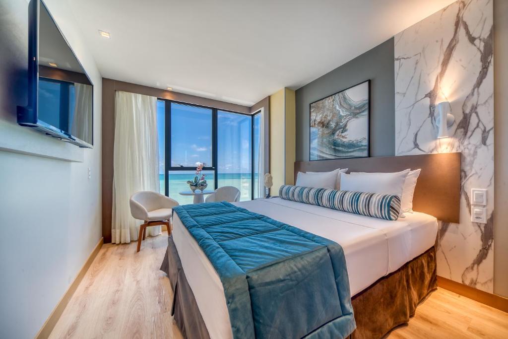 a bedroom with a large bed with a large window at Hotel Água de Coco in Maceió