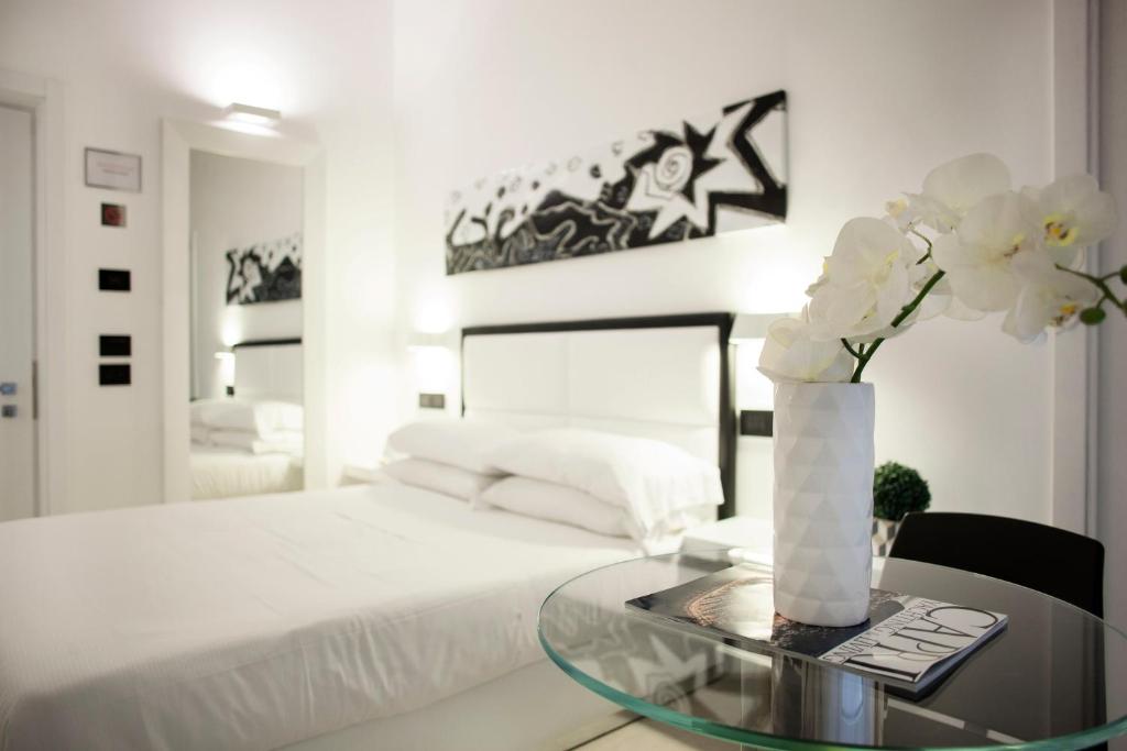 1 dormitorio con 1 cama y mesa de cristal con flores en LHP Suite Napoli Parco Margherita, en Nápoles