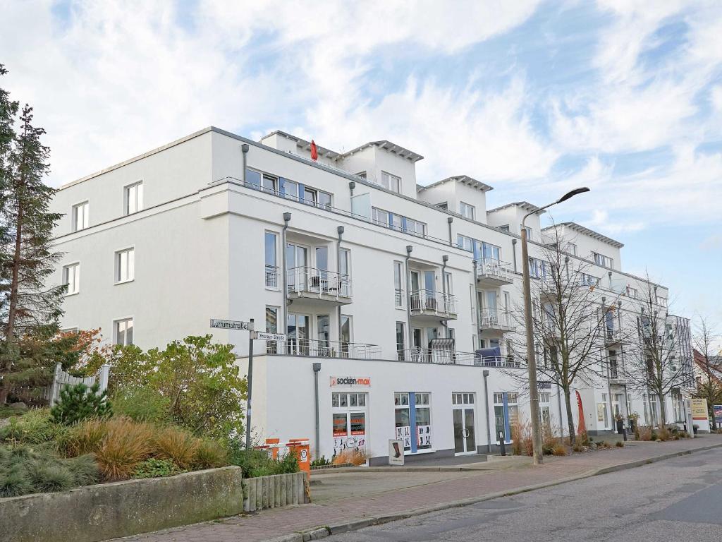un bâtiment blanc sur le côté d'une rue dans l'établissement Residenz "bel-vital" Binz - WG28 mit kleinem Meerblick und Balkon, à Binz