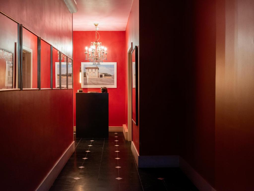 un couloir avec des murs rouges et un lustre dans l'établissement Verne Dreams, à Gand