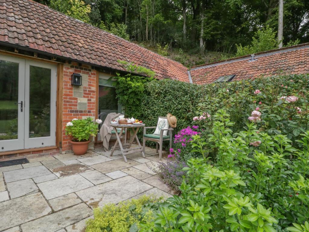 un patio con mesa y sillas en un jardín en Cow Drove Cottage en Salisbury