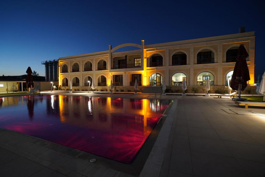 un gran edificio con una piscina frente a él por la noche en Vinum Bağ Oteli & Spa Tennis Courts By Edrine Vine, en Edirne