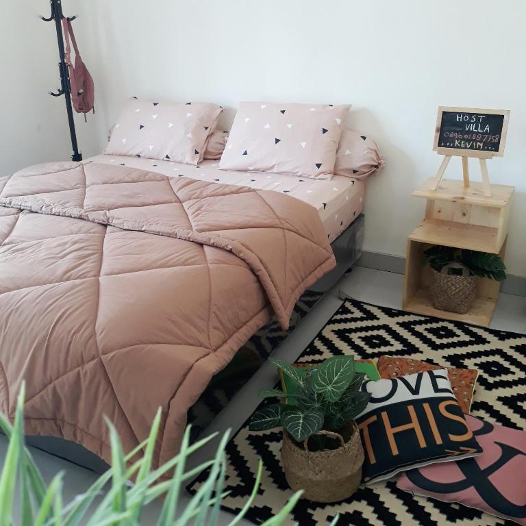 a bed with a pink comforter in a room with plants at Villa Seruni Bandungan in Bandungan