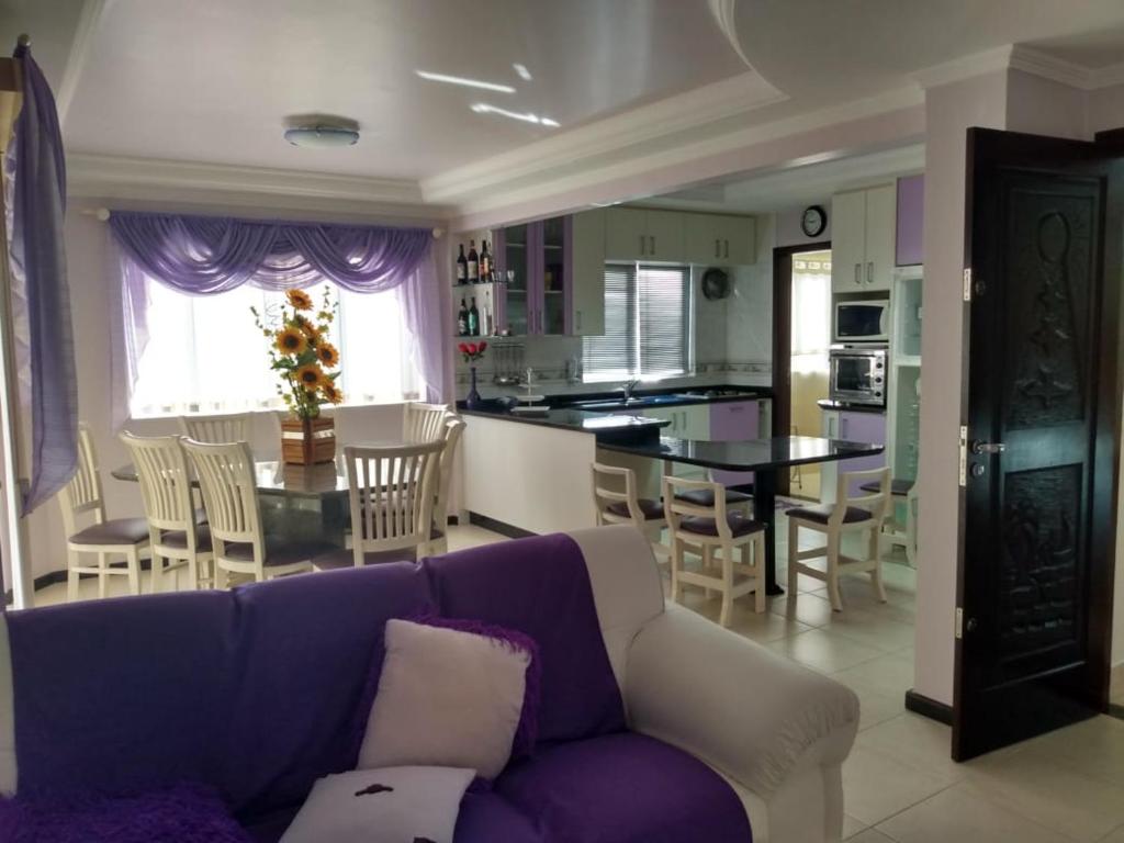 uma sala de estar com um sofá roxo e uma cozinha em Apartamento em itapema em Itapema