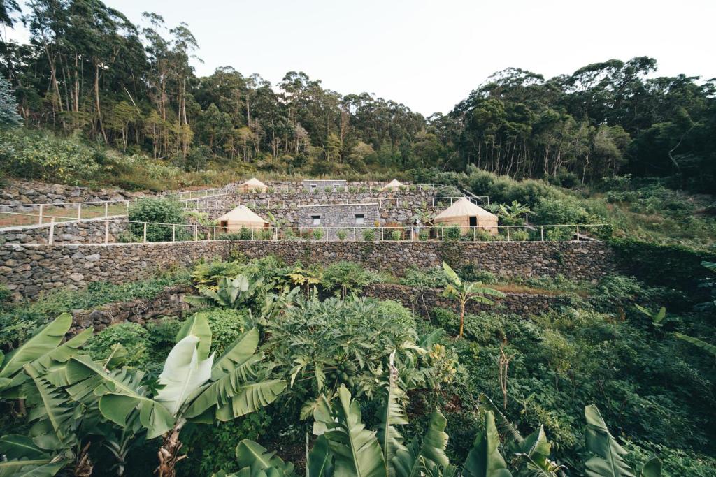 um jardim com uma parede de pedra e um edifício em Retiro Atlântico em Urzelina