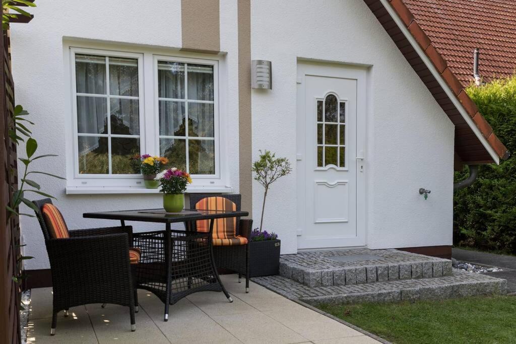 um pátio com uma mesa e cadeiras em frente a uma casa em Weide - gemütliches Ferienhaus am Anger in Kloster, Insel Hiddensee em Kloster