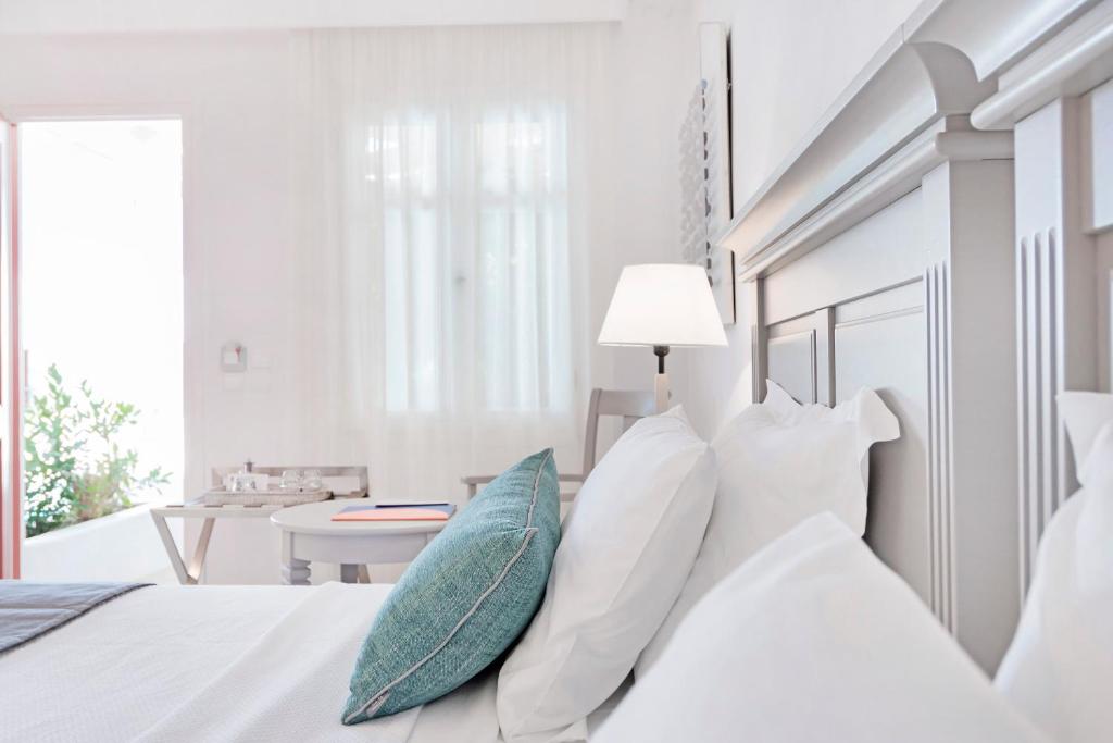 a white bedroom with a white bed with pillows at Stelia Mare Boutique Hotel in Naousa