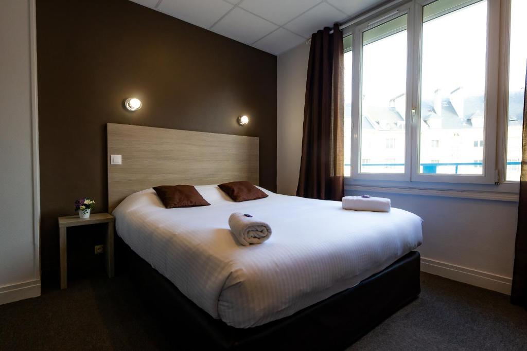 a bedroom with a large bed with a large window at Logis Hotel Du Chateau in Caen