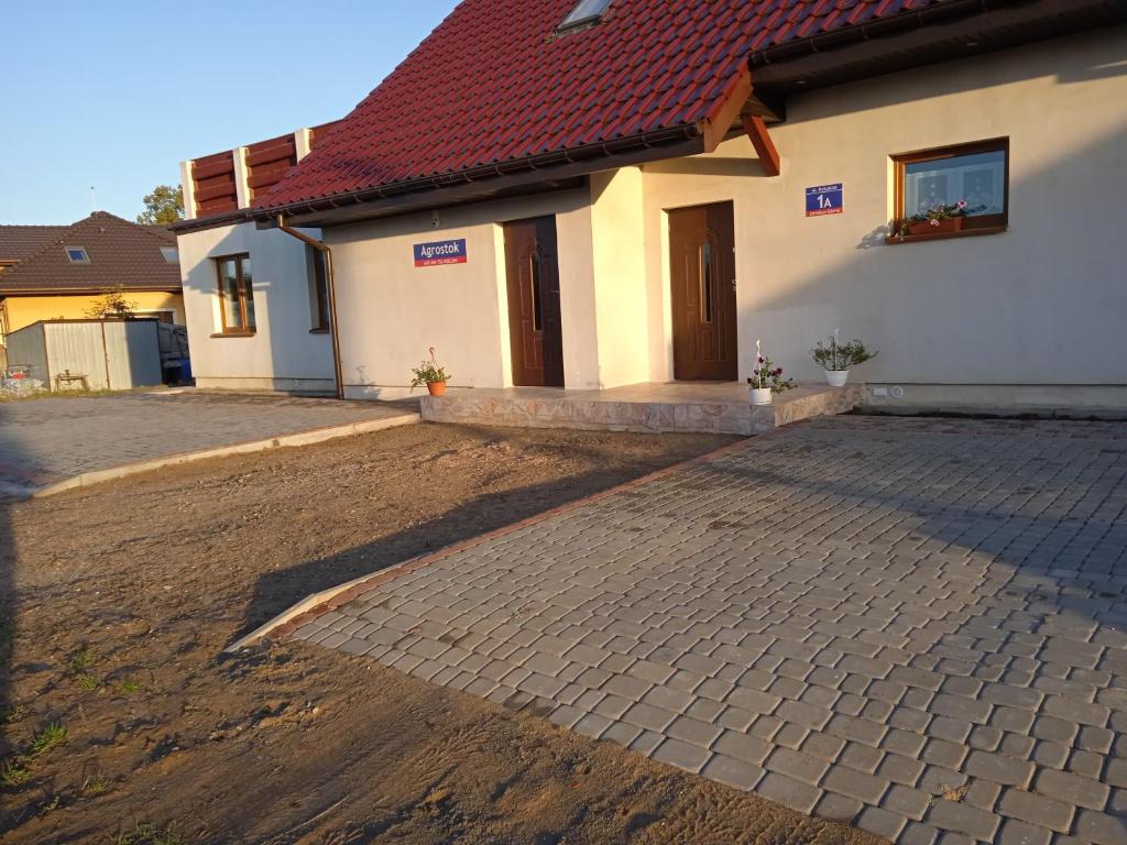 een huis met een rood dak en een stenen oprit bij Agrostok noclegi agroturystyka in Strzelce Górne
