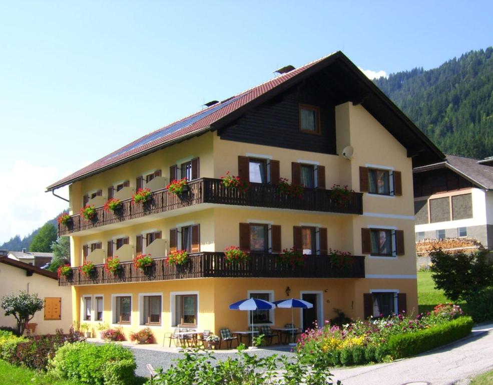 a large yellow building with balconies and tables and umbrellas at Haus Alpenfriede in Weissensee