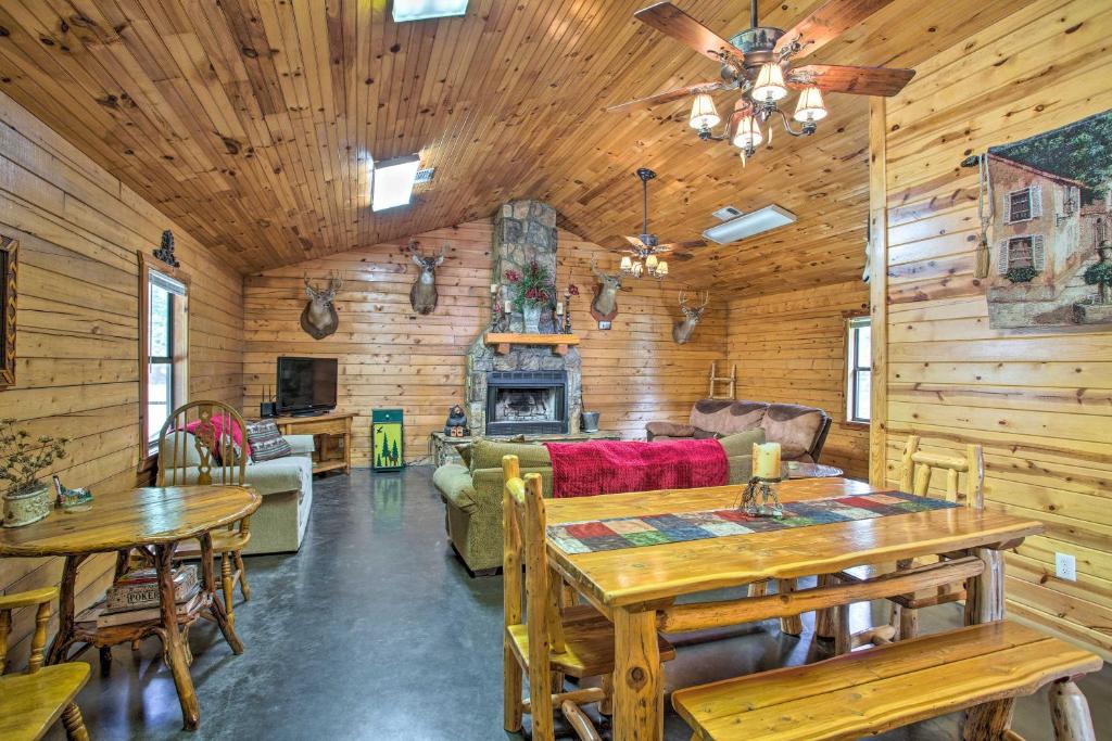 a log cabin living room with wooden walls and tables at Peaceful Pet-Friendly Retreat with Private Hot Tub! in Broken Bow