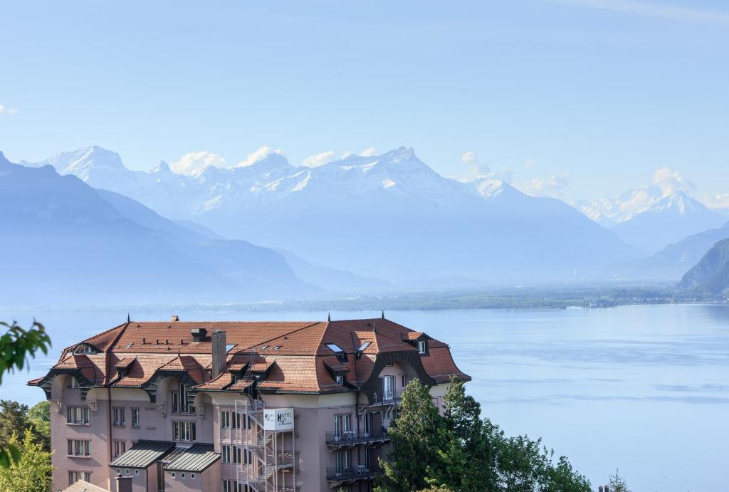 un bâtiment avec un toit carrelé et des montagnes en arrière-plan dans l'établissement Prealpina, à Chexbres