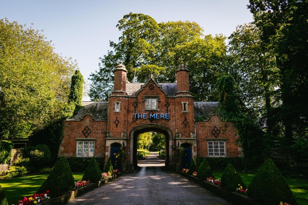 una entrada a una casa de ladrillo rojo con un cartel que dice que eran en The Mere Golf Resort & Spa, en Knutsford