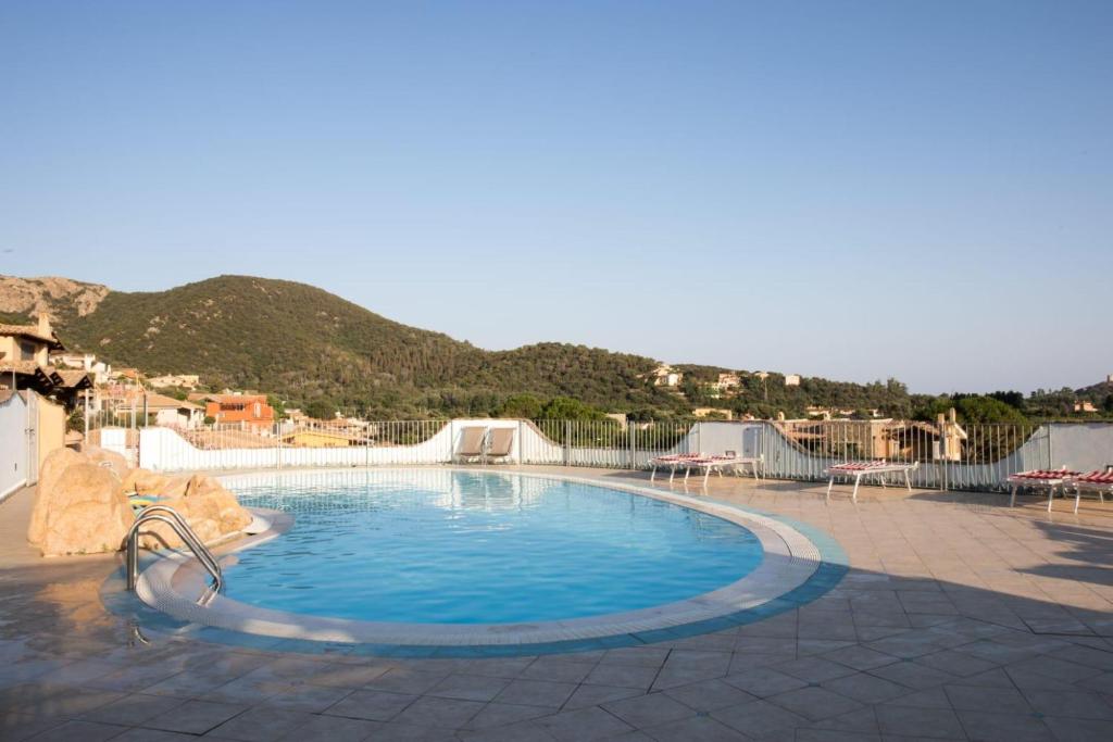 a swimming pool in a resort with a mountain in the background at Sobìa Pitticca in Chia