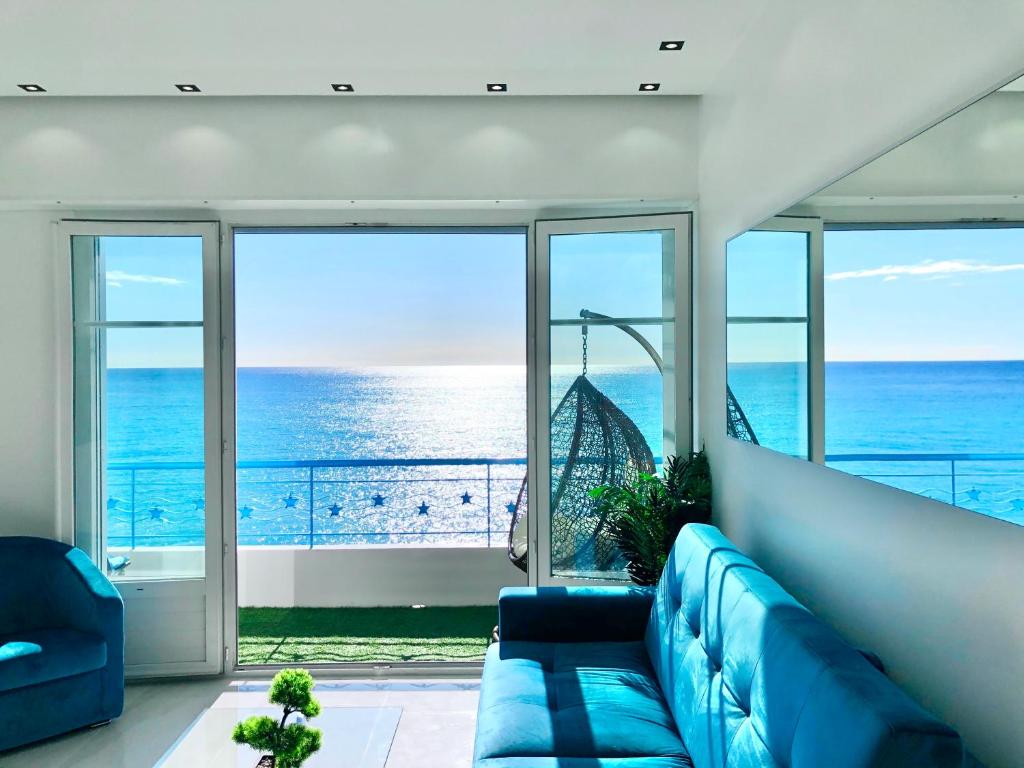 a living room with a blue couch and a view of the ocean at Sea view - Promenade des Anglais in Nice