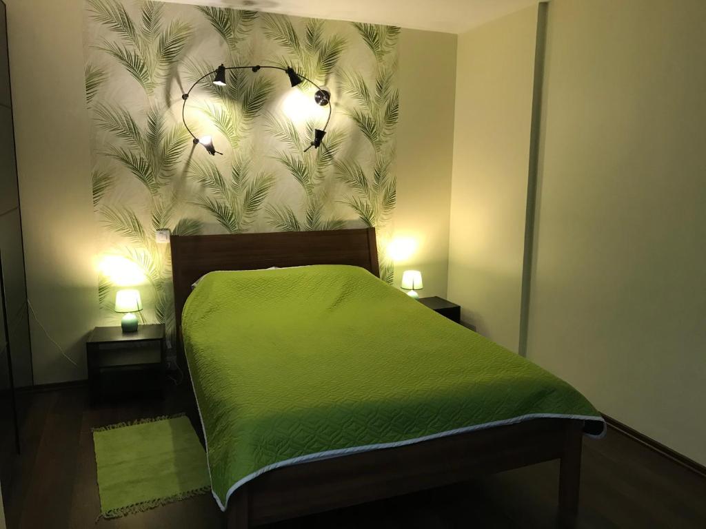 クロンシュタットにあるApartment Airinの緑のベッド1台、壁に2つの照明が付いたベッドルーム1室