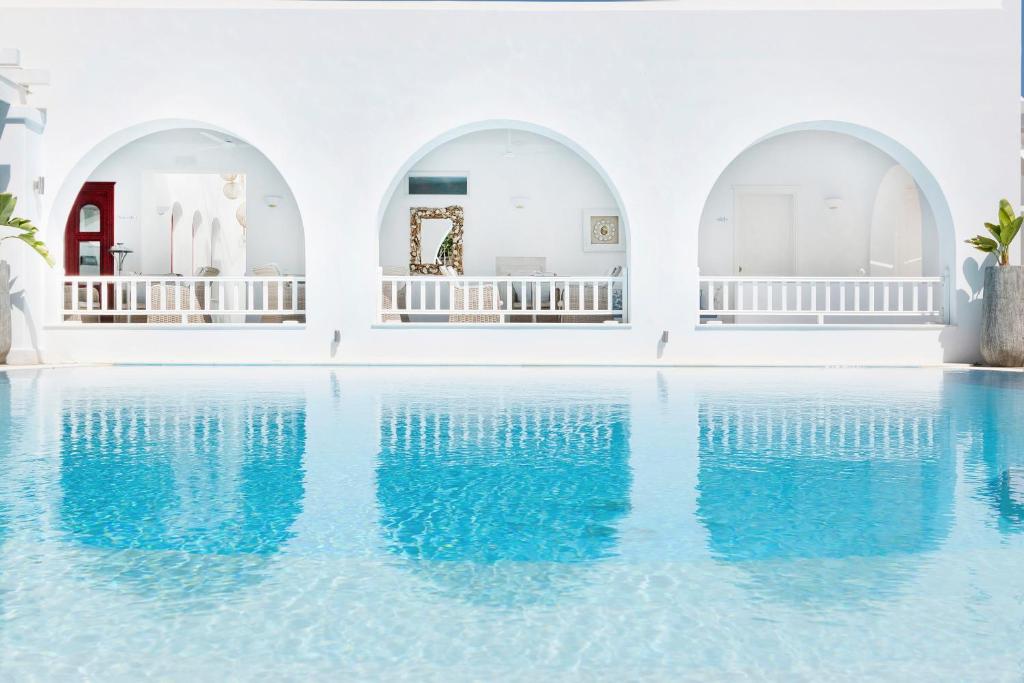 a pool with blue water in a white building at Stelia Mare Boutique Hotel in Naousa