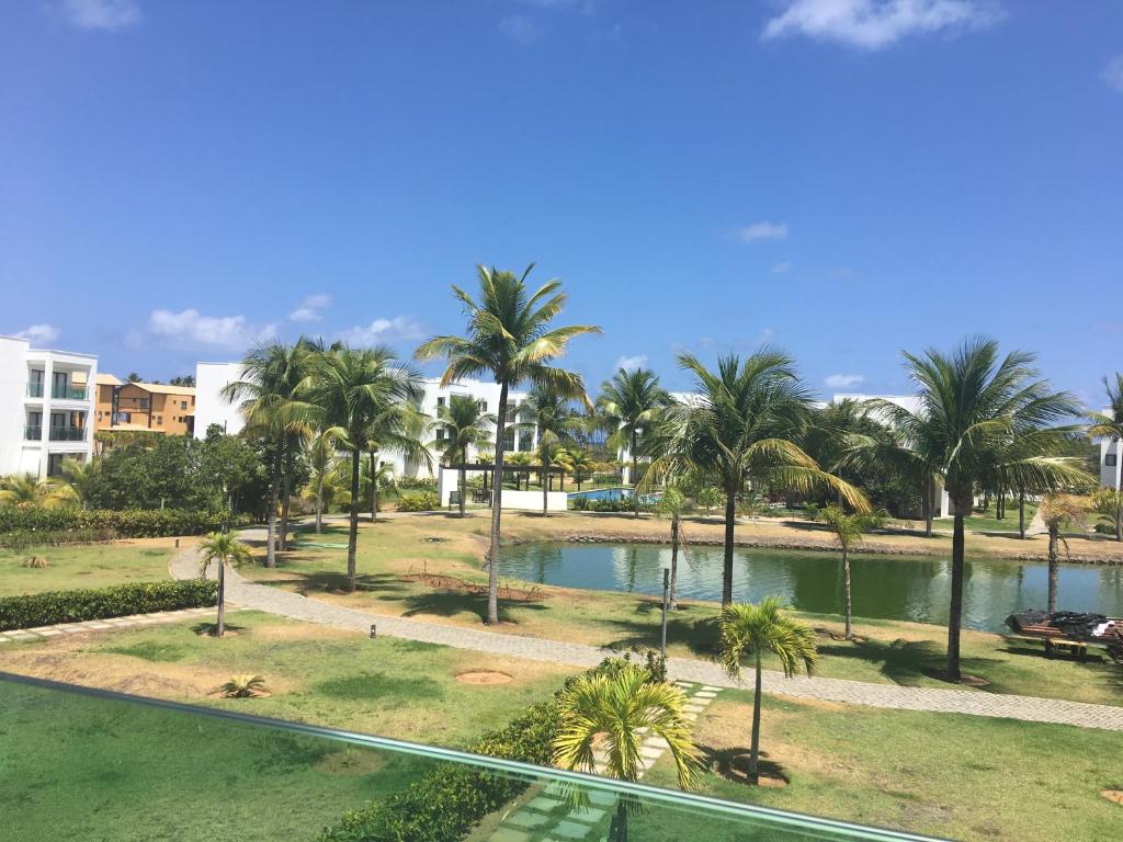 a view of a park with palm trees and a pool at Apartamento em Condominio de Luxo - Iberostar- Praia Do Forte in Praia do Forte