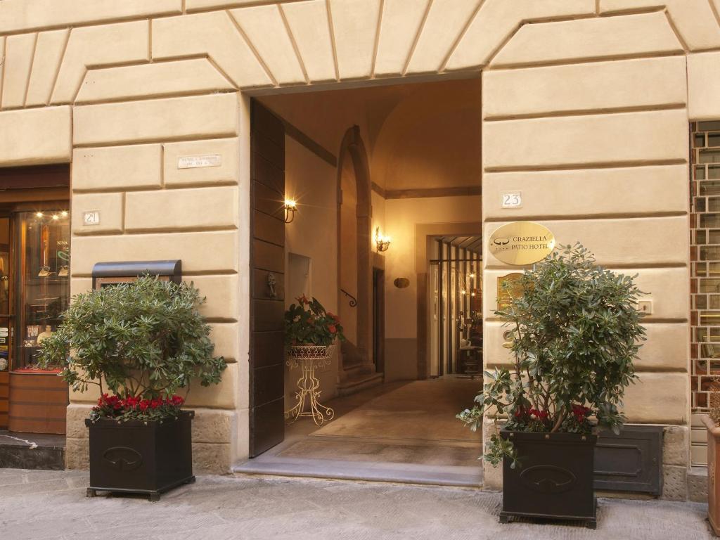 uma entrada para um edifício com dois vasos de plantas em Graziella Patio Hotel em Arezzo