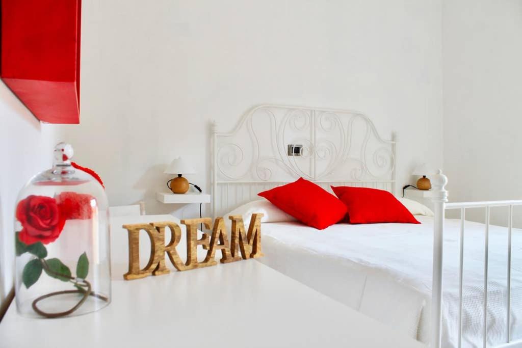 una cama blanca con almohadas rojas y un signo de sueño en ella en BORGHETTO STORICO - Fronte Castello, en Villar Dora