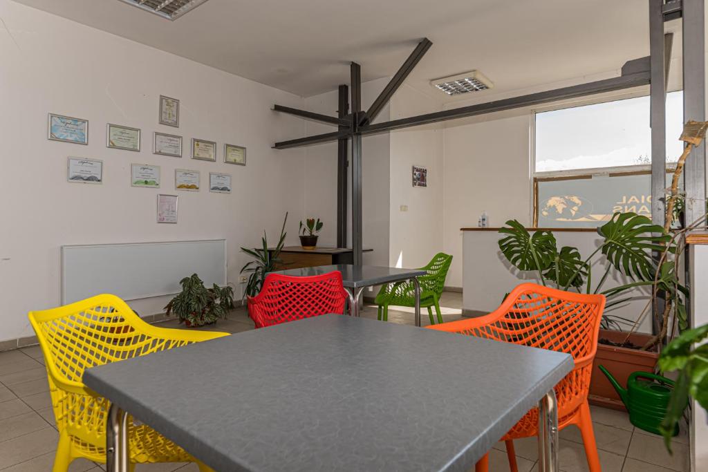 a dining room with a table and colorful chairs at Hostel Ghimbav Airport in Ghimbav