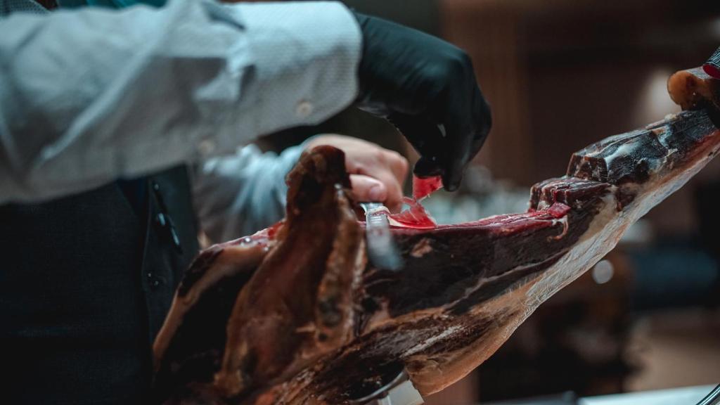 a person cutting a piece of meat with a knife at Zenit Convento San Martin in San Sebastián