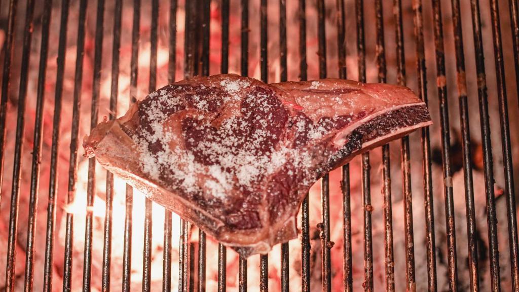 a piece of meat is cooking on a grill at Zenit Convento San Martin in San Sebastián