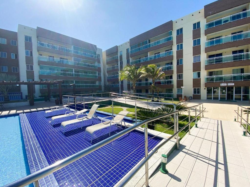 a swimming pool with lounge chairs and a building at VG Fun | Praia do Futuro - CE in Fortaleza