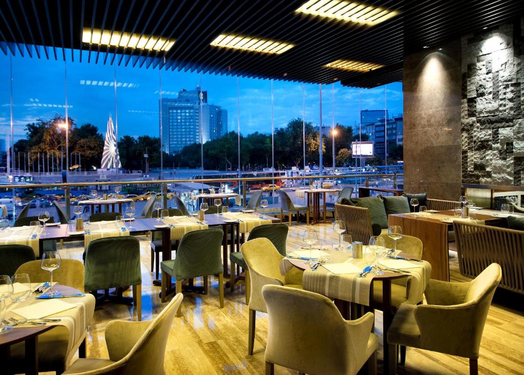 a restaurant with tables and chairs and a large window at The Marmara Taksim in Istanbul