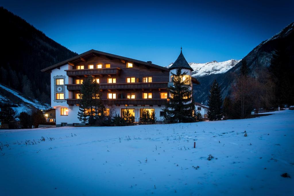 a large building with a clock tower in the snow at Hotel Hafele in Kaunertal