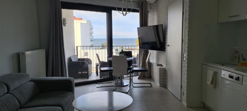 a living room with a couch and a tv and a balcony at Apartament Horyzont in Międzyzdroje