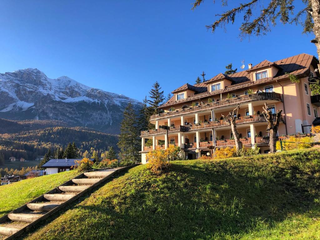 duży budynek na wzgórzu z górami w tle w obiekcie Boutique Hotel Villa Blu Cortina D'Ampezzo w mieście Cortina dʼAmpezzo