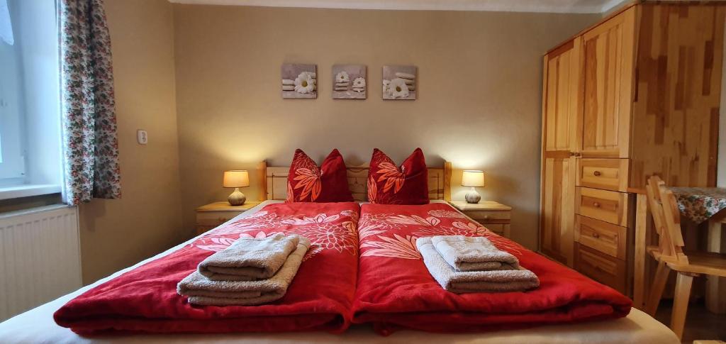 ein Schlafzimmer mit einem roten Bett mit Handtüchern darauf in der Unterkunft Privát u Babičky in Ždiar