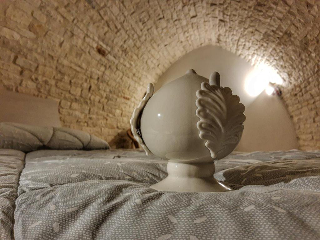 a white vase sitting on top of a bed at Mirum Apuliae 16 in Alberobello