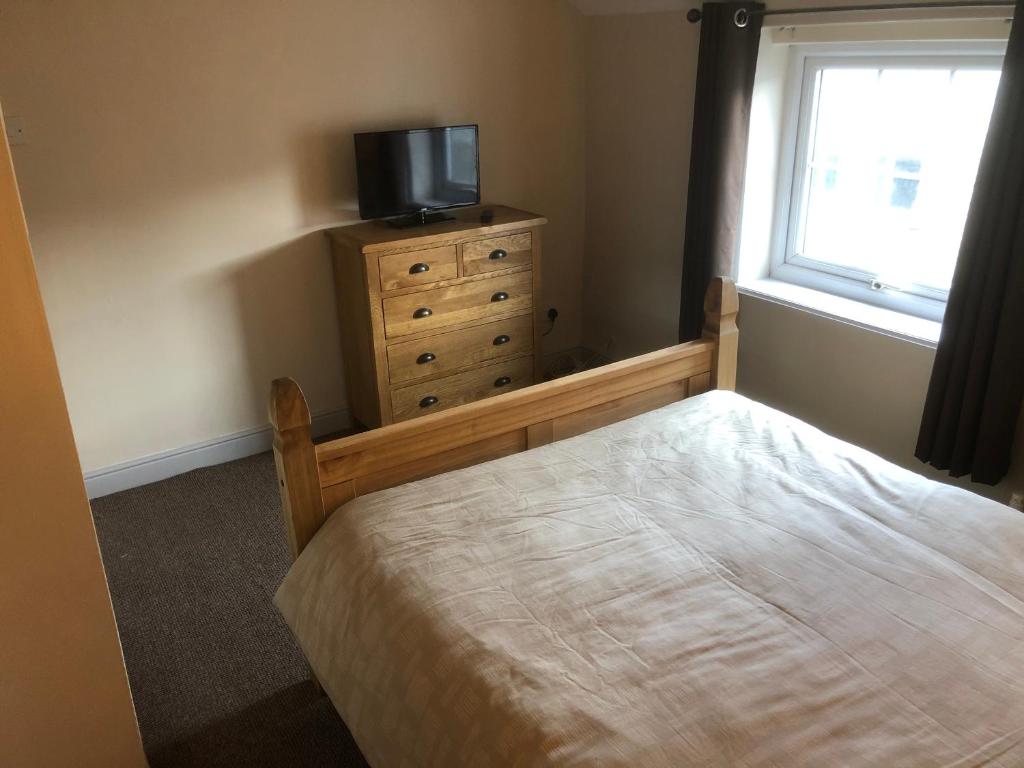 een slaapkamer met een bed en een televisie op een dressoir bij Rhos St Retreat in Ruthin