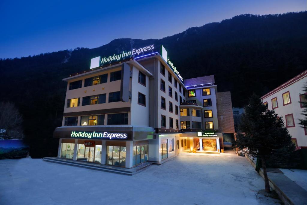 Holiday Inn Express Jiuzhaigou, an IHG Hotel في جيوتشايقو: فندق وسط مواقف في الثلج