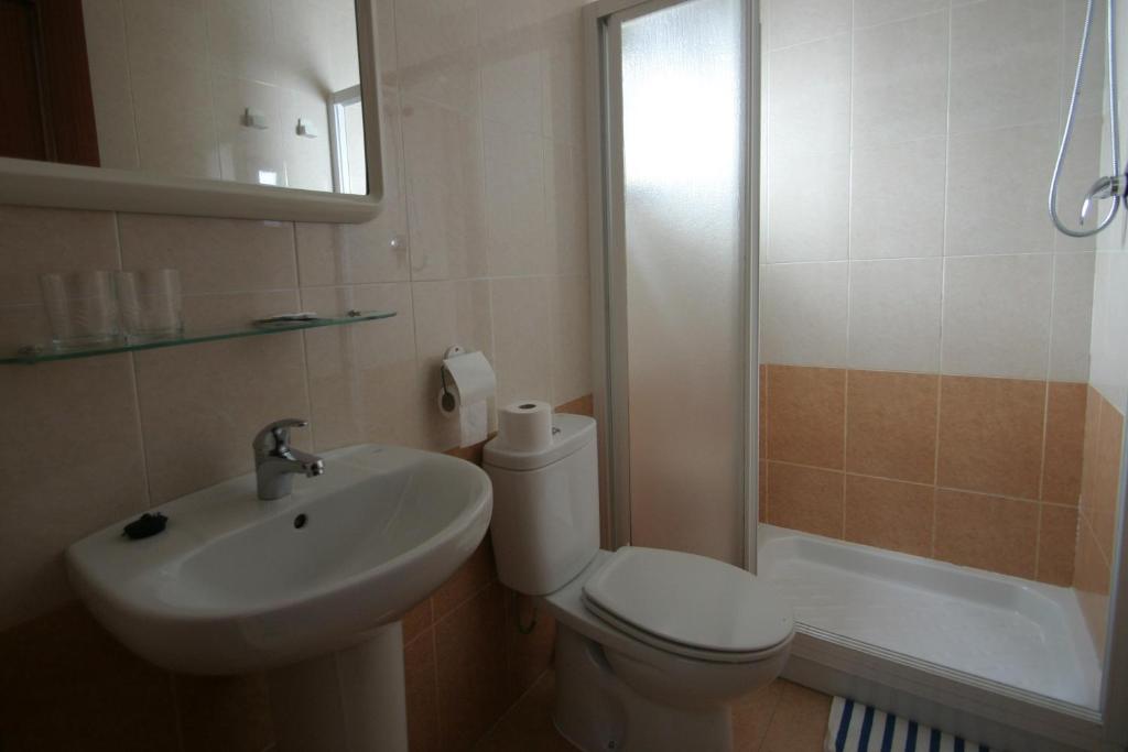 Un baño con inodoro, lavabo y ducha. en Pension el Portillo, en Córdoba