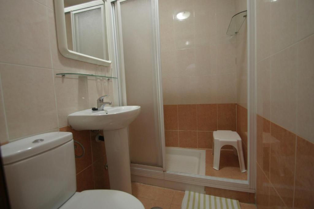 Un baño con inodoro, lavabo y ducha. en Pension el Portillo, en Córdoba