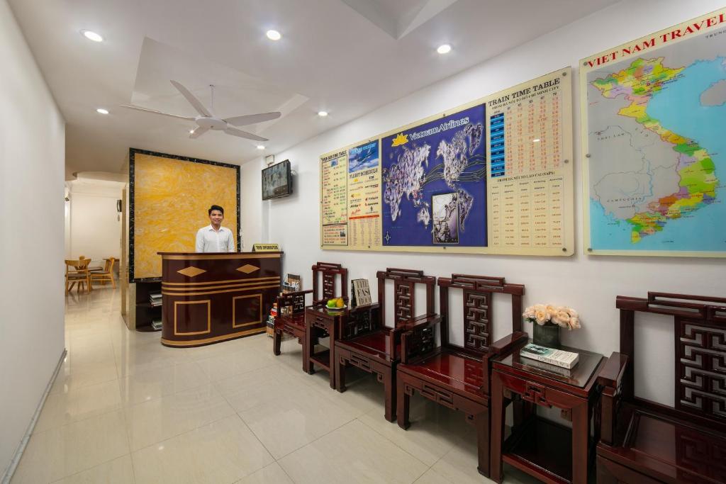 a man standing behind a podium in a room with a map at Little Hanoi Hotel in Hanoi