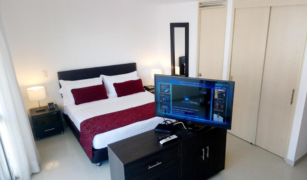 1 dormitorio con 1 cama y mesa con TV en AMOBLADOS MCCORMICK, en Bucaramanga