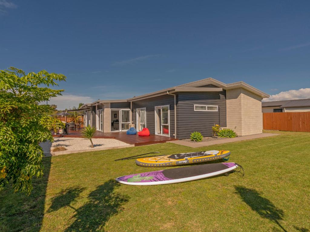 two surfboards sitting on the grass in front of a house at Modern Beach Pad - Whitianga Holiday Home in Whitianga