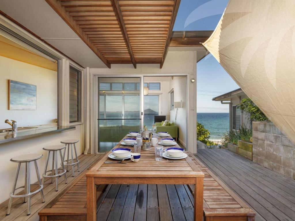 a dining table on a deck with a view of the ocean at Sea Shack in Seal Rocks
