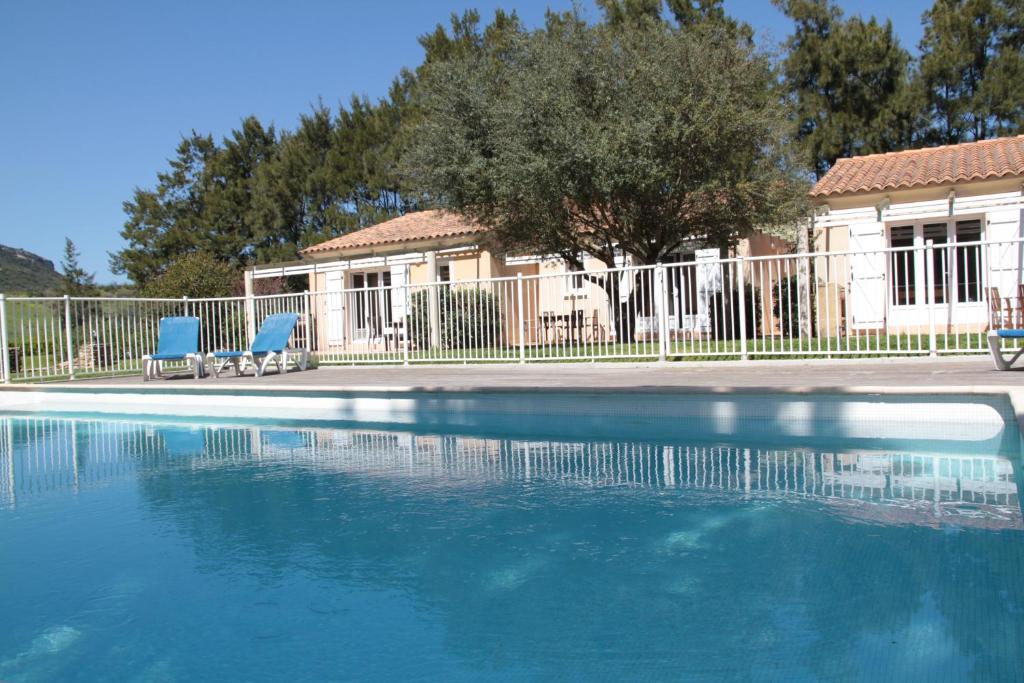 a swimming pool with two blue chairs and a house at Domaine Les 4 Vents in Patrimonio