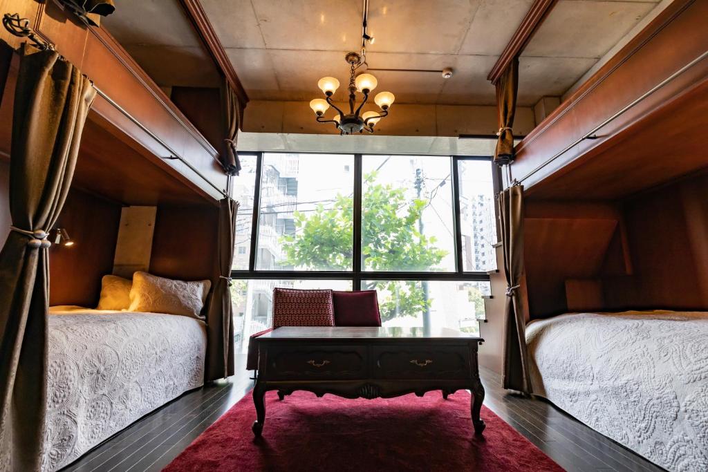 a bedroom with two beds and a table in front of a window at Creare Ryogoku in Tokyo
