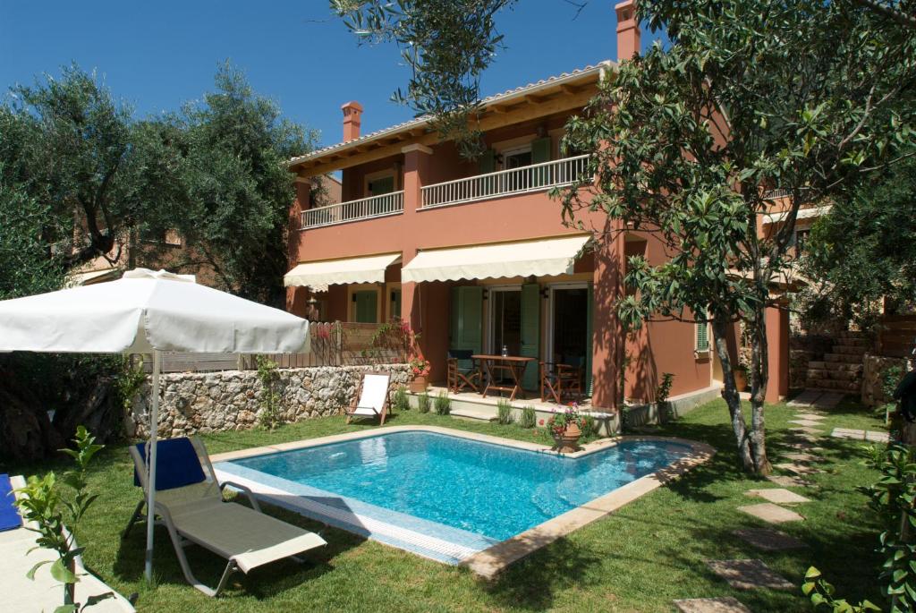 a villa with a swimming pool in front of a house at La Riviera Barbati Seaside Apartments & villas in Barbati