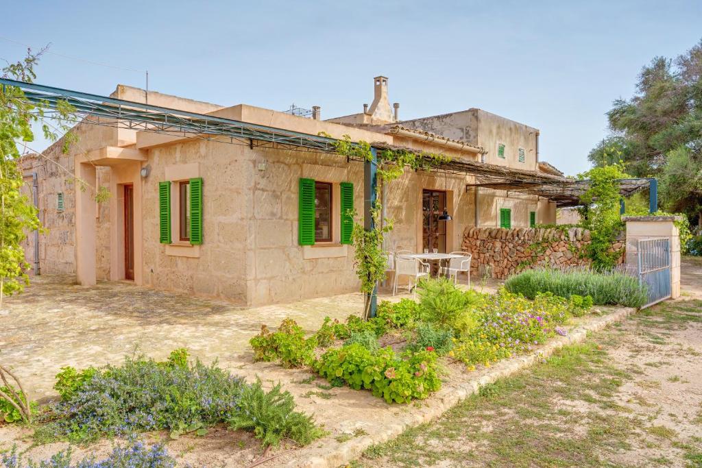 una casa antigua con persianas verdes y jardín en Possessio Sa Barrala El Taller, en Campos