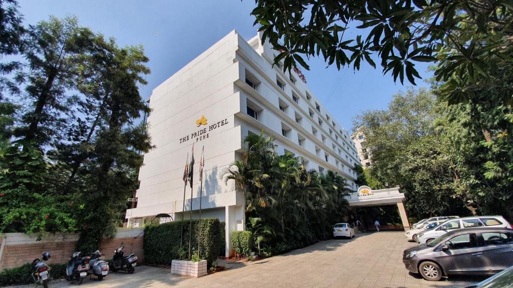 ein weißes Gebäude mit Motorrädern, die davor geparkt sind in der Unterkunft Pride Hotel Pune in Pune