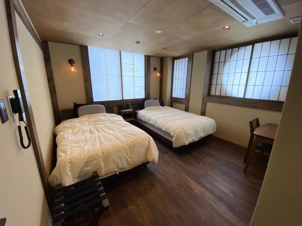 two beds in a room with windows at 日月庵 BnB Sunmoon in Kanazawa